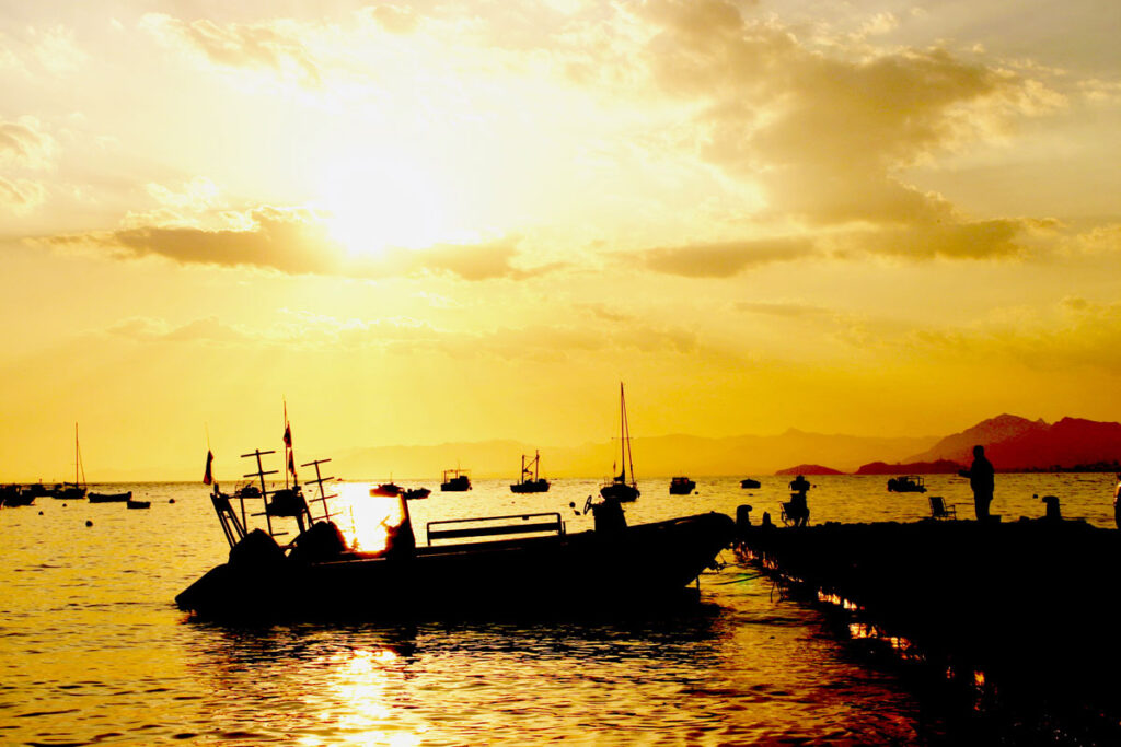 Boot im Wasser im spanischen Azohia. Angler angeln vom Steg aus.